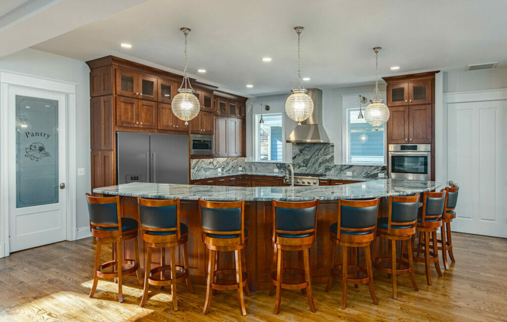 Traditional Kitchen - Golden Rule Builders - Kitchen remodel / renovation, Large, open kitchen, with a large granite island and counters, beautiful dark wood cabinets and flooring, modern hanging lights, and stainless steel appliances