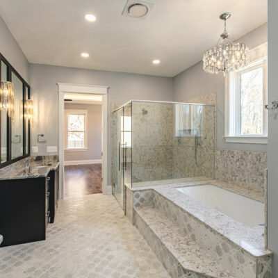 Elegant Master Bathroom Renovation - Golden Rule Builders - Bathroom remodel / renovation, a view from the beautiful master bathroom that contains, double vanities, a large walk in closet, large bathtub with a chandelier above, and a big walk in shower, all looking into the master bedroom